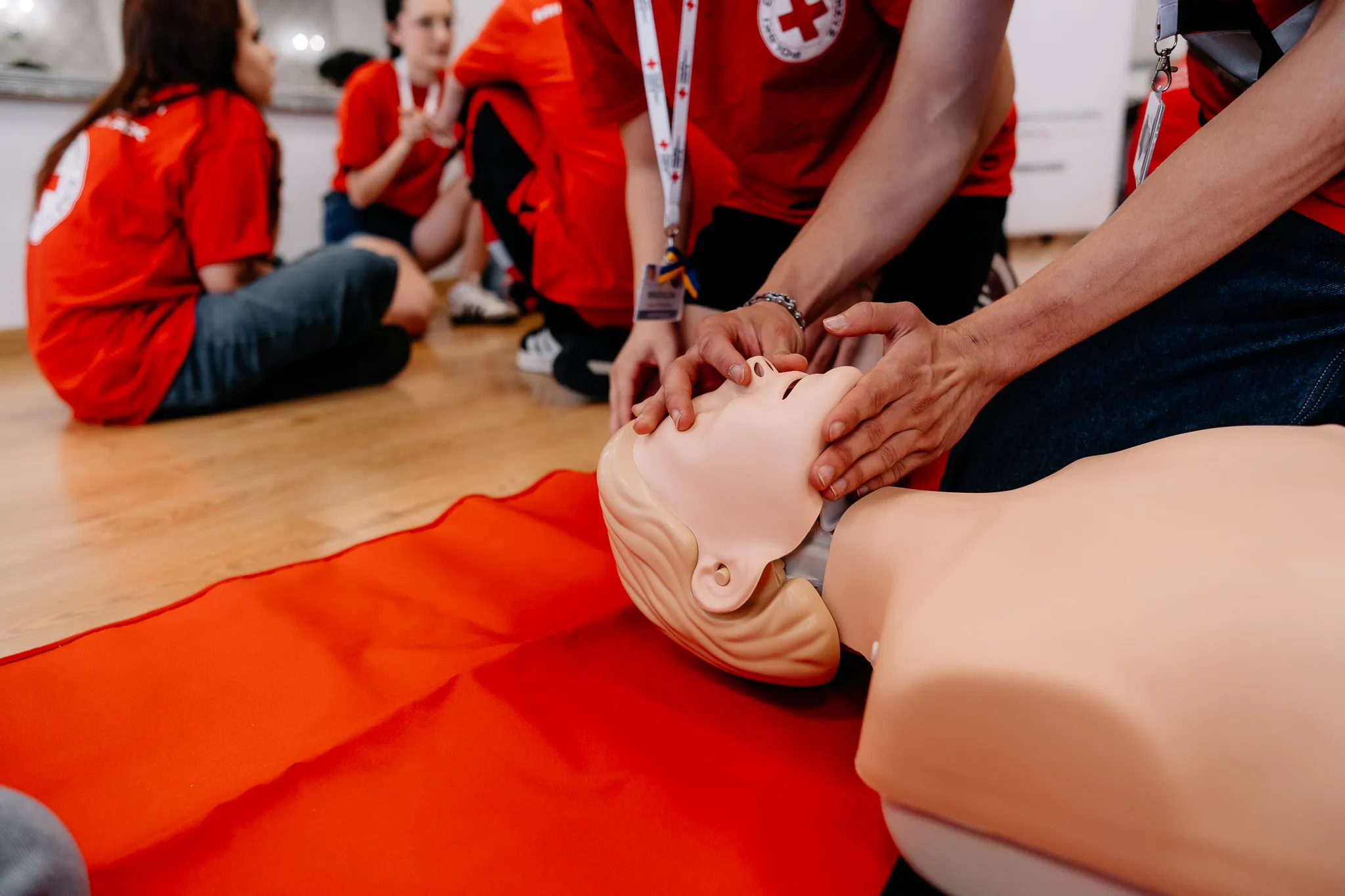 Dłonie podnoszą podbródek i uciskają nos fantoma podczas kursu pierwszej pomocy PCK
