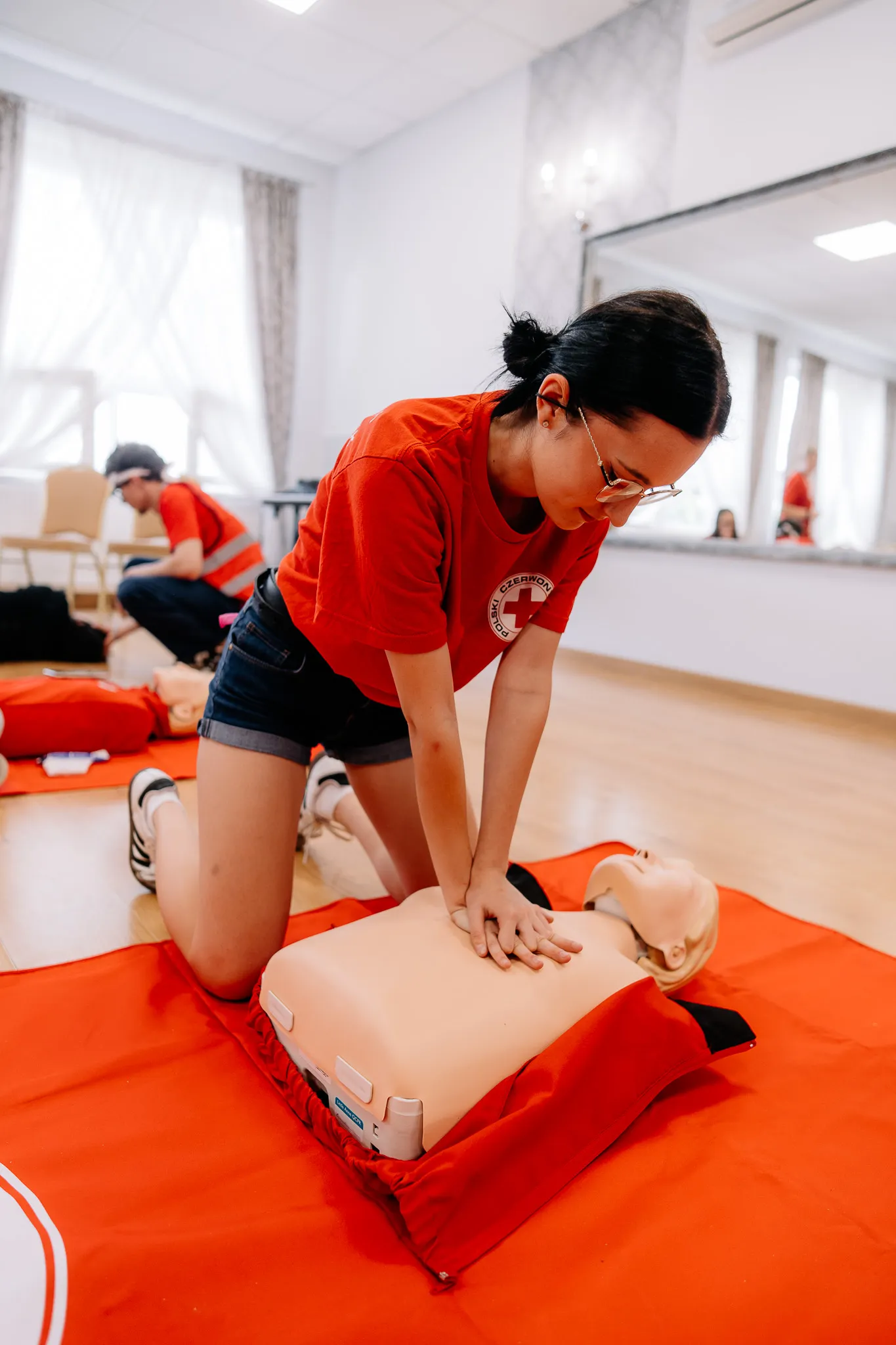 Młoda kobieta uciska fantom podczas kursu pierwszej pomocy