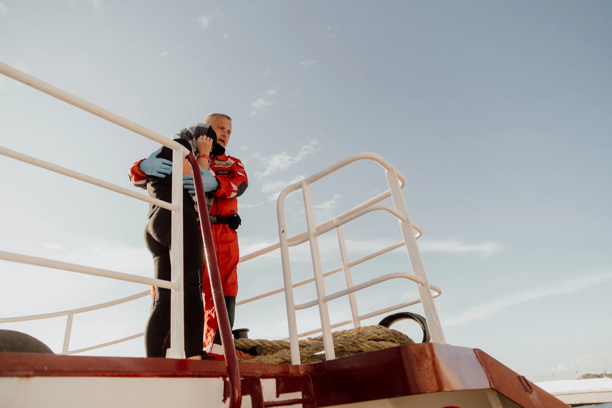 Ratownik PCK delikatnie obejnuje ubraną na czarną kobietę