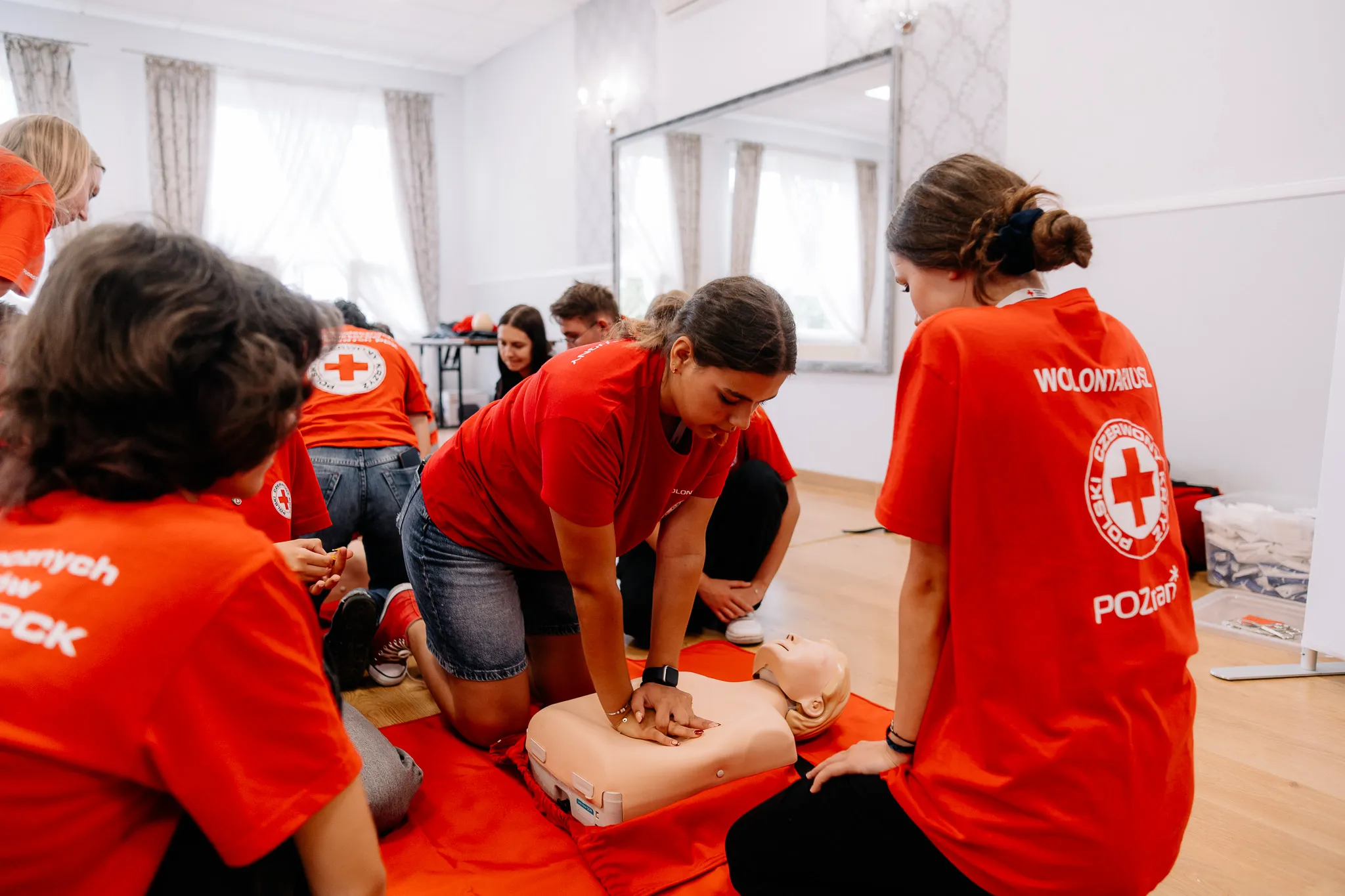 Młoda kobieta uciska fantom podczas kursu pierwszej pomocy PCK